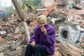 Elderly woman near the destroyed house