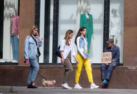 Girls pass by a man begging for alms