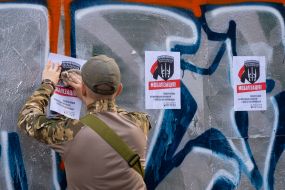 Военнослужащий расклеивает информационные листовки о мобилизации в Киеве