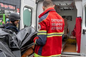 Doctors load the corpse of a murdered man into an ambulance in Kharkiv