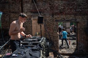 Volunteers clean up the rubble of the House of Culture in the village of Yagidne to the accompaniment of electronic music