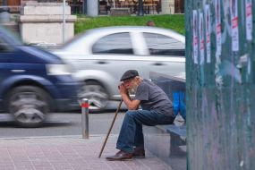 Elderly man sitting by the road