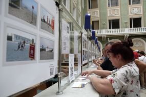 Visitors to the "Good evening, we are from Ukraine" stamp redemption campaign near the windows with photos