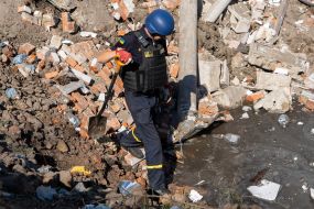An employee of the State Emergency Service collects debris in a ravine near a medical laboratory destroyed by rocket fire