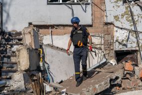 An employee of the State Emergency Service collects debris in a ravine near a medical laboratory destroyed by rocket fire