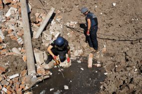 An employee of the State Emergency Service collects debris in a ravine near a medical laboratory destroyed by rocket fire