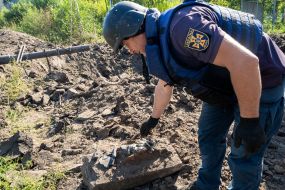 An employee of the State Emergency Service collects debris in a ravine near a medical laboratory destroyed by rocket fire