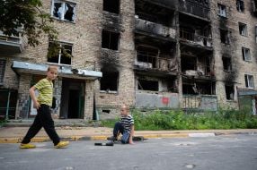 Мальчики возле разрушенного в результате обстрелов российских оккупантов жилого дома