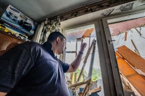 The man shows the destroyed balcony in the apartment