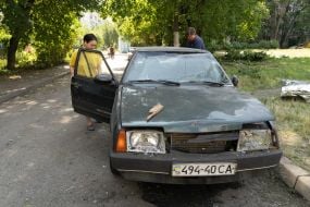 A man and a woman near a car damaged by an explosion in one of Kharkiv's residential areas