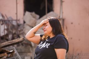 A woman is crying near the ruins of a destroyed house