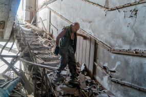 A man walks down the stairs in a ruined building