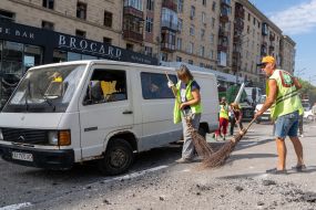 Рабочие убирают разбитые стекла и мусор возле Дома недвижимости