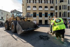 Workers clean up broken glass and debris near the Real Estate House