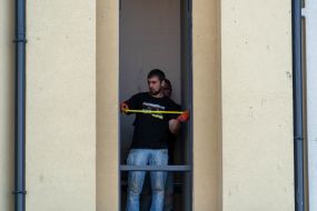 A man measures the size of a broken window in the Real Estate House