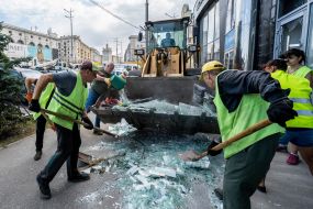Workers clean up broken glass and debris near the Real Estate House