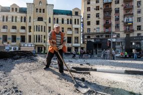 Мужчина убирает выбитые стекла в Доме недвижимости