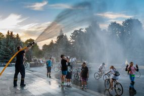 A rescuer waters the participants of the Big City Ride charity bike race from a hydrant