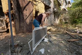 Місцева мешканка біля пошкодженого від вибуху будинку