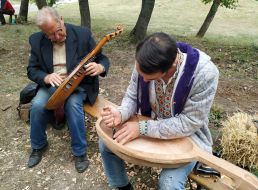 A carver cuts a bandura out of wood