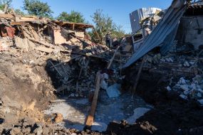 Вирва біля зруйнованого після ракетного обстрілу будинку