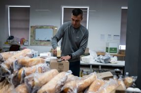 A voluntA volunteer packs boxes of food