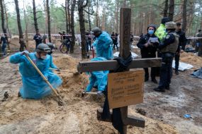 Forensic experts excavate a fresh grave at the site of a mass burial in a forest near the town of Izyum
