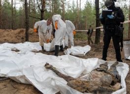 Forensic experts move the bodies removed from the mass grave to the site of mass burials in the forest near the city of Izyum