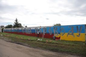Местные жители перекрашивают забор в цвета украинского флага