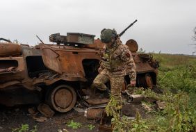 A soldier of the National Guard of Ukraine near a burned-out Russian armored personnel carrier