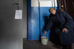 An elderly woman on the stairwell in a house damaged by a MLRS salvo