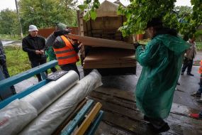 Volunteers unload wood panels from a truck to repair broken windows