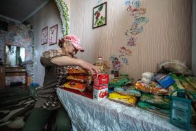 An elderly woman reviewing humanitarian aid in her apartment