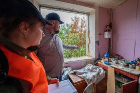 Volunteers measure the size of a window shattered by an explosion in a house damaged by a MLRS salvo
