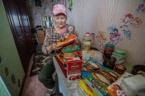 An elderly woman reviewing humanitarian aid in her apartment