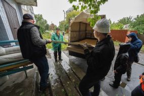Volunteers unload wood panels from a truck to repair broken windows