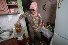 An elderly woman reviewing humanitarian aid in her apartment