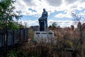 Monument to the fallen soldiers in World War II against the backdrop of a destroyed house