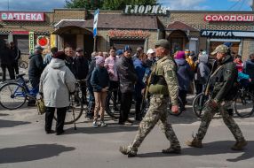The military of the Armed Forces of Ukraine pass near the locals in Izyum city