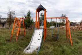 Playground against the background of a destroyed house in Prudyanka village