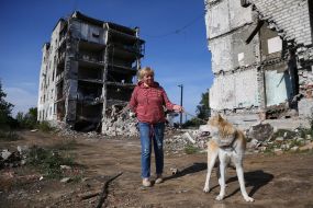 A local resident walks her dog near her house destroyed by Russian occupiers' shelling, in Izyum