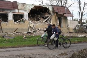 Местные жители проходят возле разрушенного кафе в селе Петропавловка