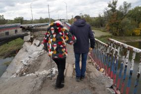 Люди идут по полуразрушенному мосту в Купянске