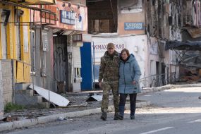 People walk past destroyed houses in the city of Kup'yansk