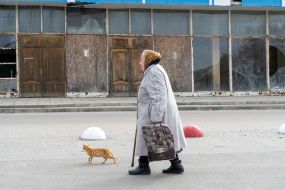 A woman walks past a destroyed store in the village of Shevchenkove