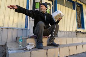 A local resident sits on the steps of a store in the city of Kupyansk