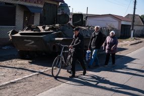 Местные жители проходят возле военной техники оккупантов