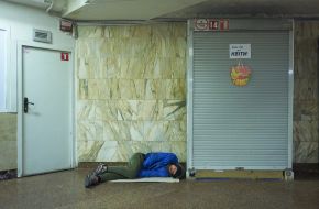 A homeless man sleeps in an underpass