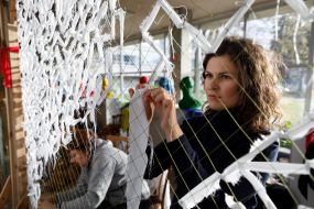 Volunteers weave camouflage nets