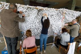 Volunteers weave camouflage nets